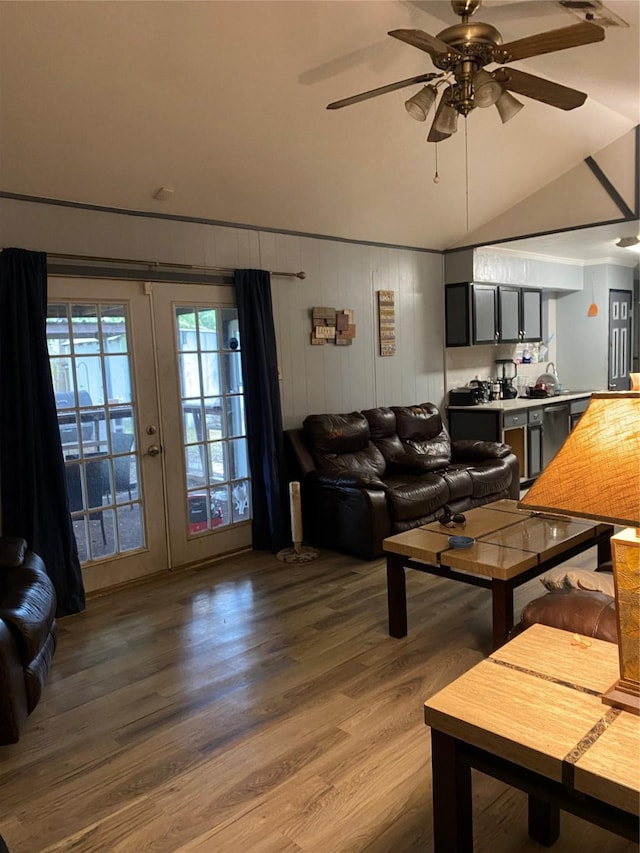 living room featuring ceiling fan, hardwood / wood-style floors, wood walls, and lofted ceiling