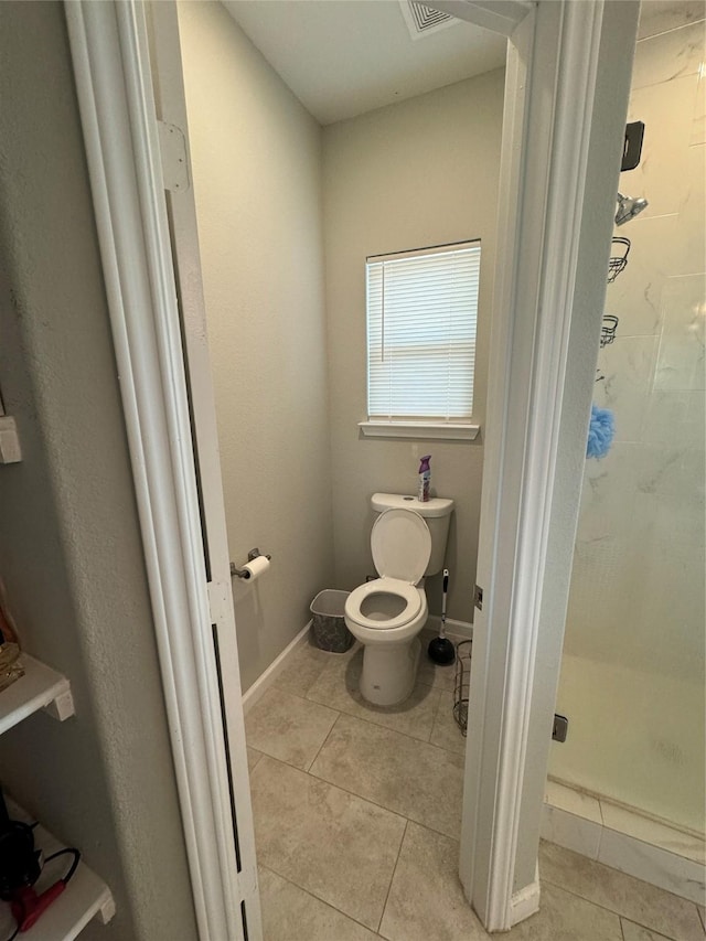 full bathroom with tile patterned flooring, toilet, a stall shower, and baseboards