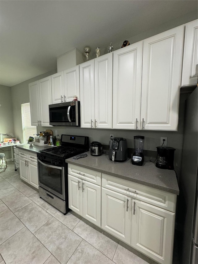 kitchen with light tile patterned floors, white cabinetry, and appliances with stainless steel finishes