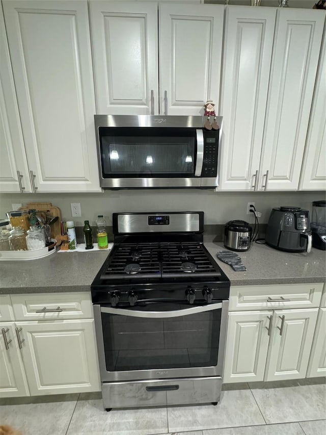 kitchen with white cabinetry, light tile patterned floors, and appliances with stainless steel finishes