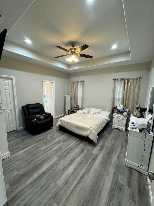 bedroom with a tray ceiling, baseboards, ceiling fan, and wood finished floors
