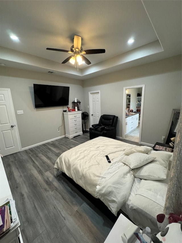 bedroom featuring a raised ceiling, ceiling fan, a closet, and dark hardwood / wood-style floors