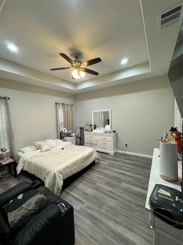 bedroom featuring ceiling fan, a raised ceiling, and wood-type flooring