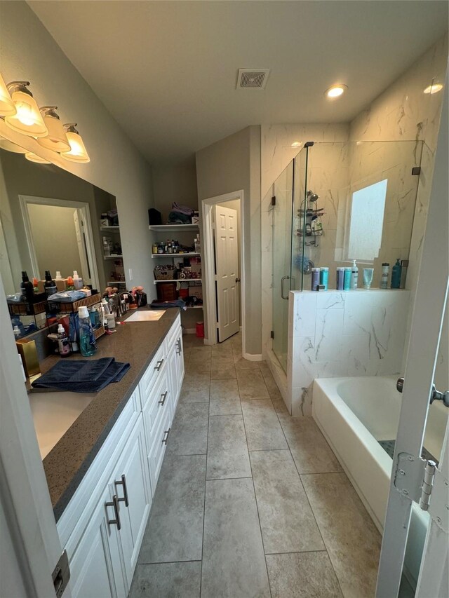 bathroom with a sink, a tub to relax in, double vanity, a marble finish shower, and tile patterned floors