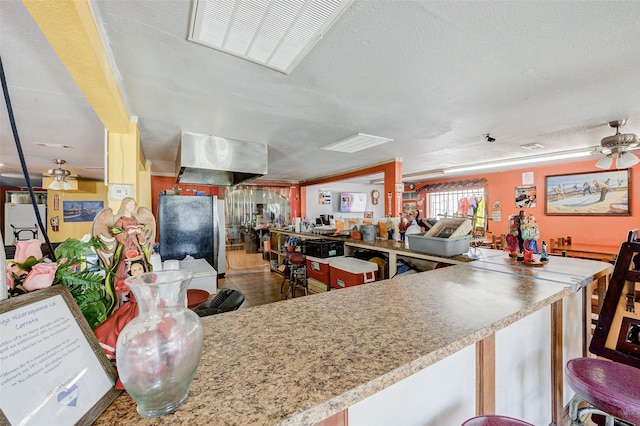 kitchen with stainless steel refrigerator, ceiling fan, tile patterned floors, kitchen peninsula, and a textured ceiling