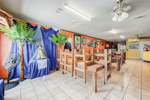 dining space with tile patterned flooring, ceiling fan, and a textured ceiling