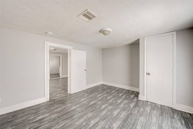 unfurnished room featuring dark hardwood / wood-style flooring and a textured ceiling