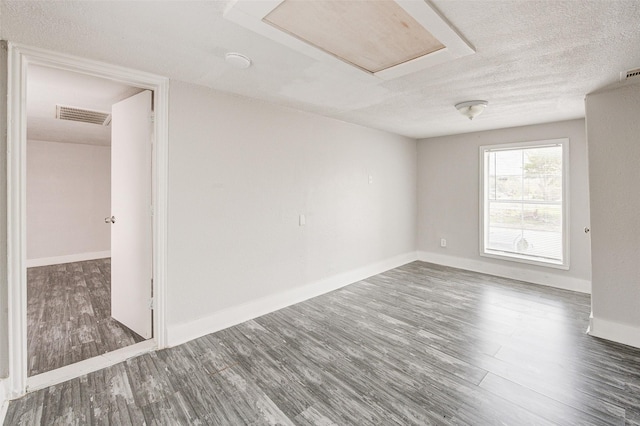 spare room featuring dark hardwood / wood-style flooring and a textured ceiling