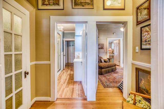 hallway with light wood-type flooring and ornamental molding