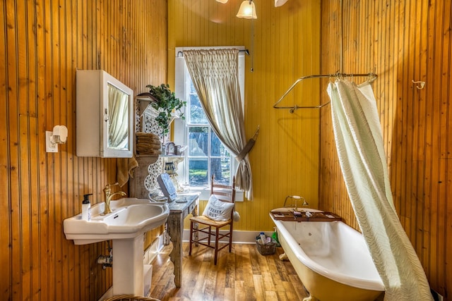 bathroom featuring wood walls, a bath, and hardwood / wood-style flooring