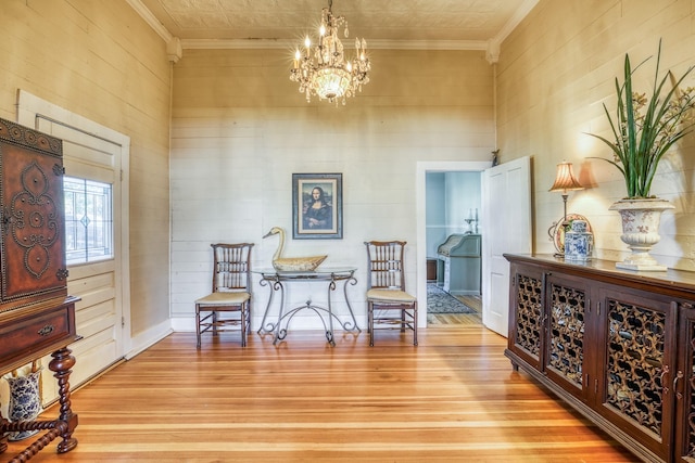 sitting room featuring crown molding, an inviting chandelier, and light wood-type flooring