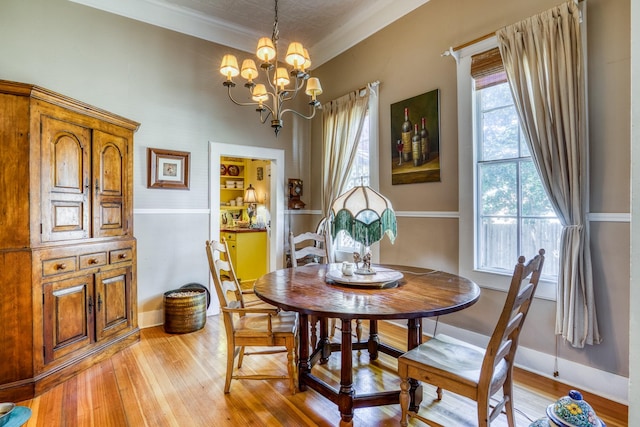 dining area featuring a chandelier, light wood-type flooring, plenty of natural light, and ornamental molding