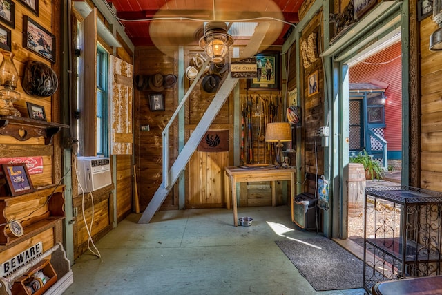 misc room featuring ceiling fan and wood walls