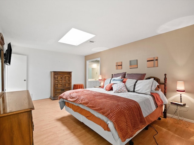 bedroom with a skylight and light hardwood / wood-style flooring