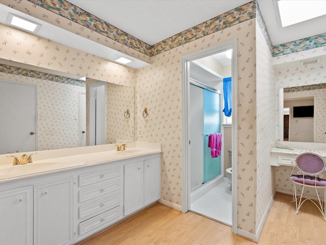 bathroom featuring vanity, toilet, wood-type flooring, and walk in shower