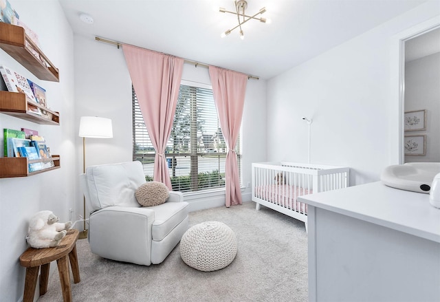 bedroom with a crib, a chandelier, and light colored carpet