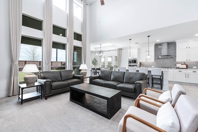 carpeted living room featuring a towering ceiling and a notable chandelier