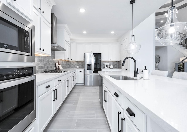 kitchen featuring sink, wall chimney exhaust hood, hanging light fixtures, and appliances with stainless steel finishes