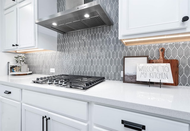 kitchen with tasteful backsplash, white cabinets, wall chimney exhaust hood, and stainless steel gas stovetop