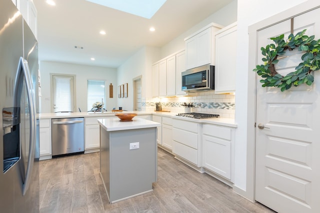 kitchen with a center island, kitchen peninsula, light hardwood / wood-style flooring, white cabinetry, and stainless steel appliances