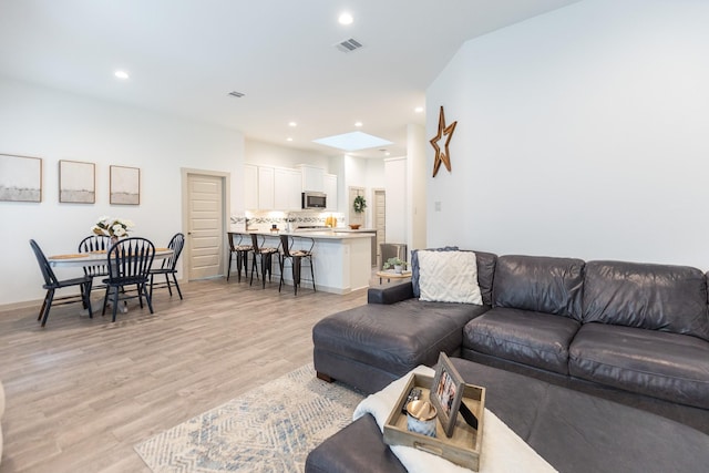 living room with light wood-type flooring and a skylight