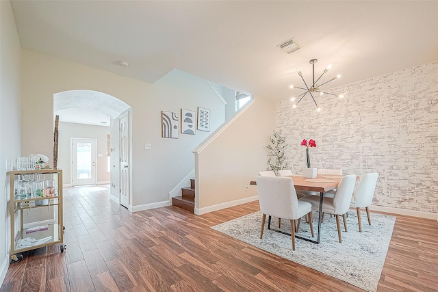 dining space with wood-type flooring and an inviting chandelier