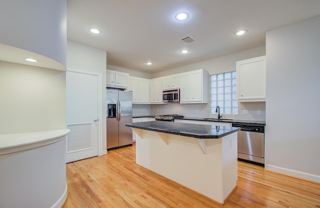 kitchen with white cabinetry, a breakfast bar, a kitchen island, and stainless steel appliances