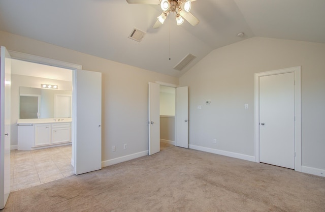 unfurnished bedroom with light colored carpet, vaulted ceiling, ceiling fan, and ensuite bathroom