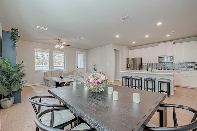 dining space featuring visible vents and light wood-style flooring