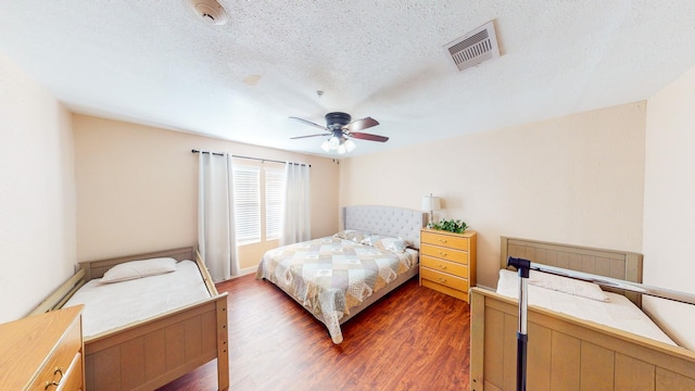 bedroom featuring ceiling fan, dark hardwood / wood-style flooring, and a textured ceiling