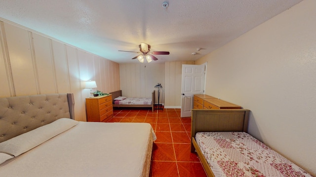 bedroom featuring ceiling fan, tile patterned flooring, and a textured ceiling