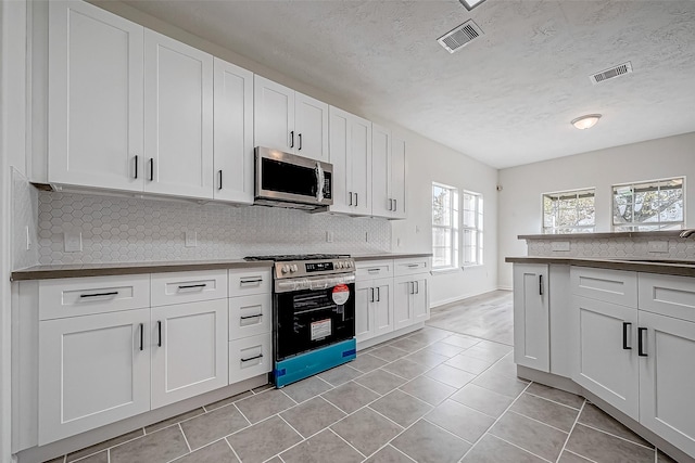 kitchen featuring white cabinets, appliances with stainless steel finishes, and light tile patterned flooring