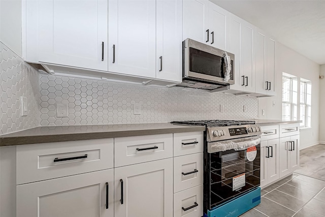 kitchen featuring white cabinets, stainless steel appliances, tasteful backsplash, and light tile patterned flooring