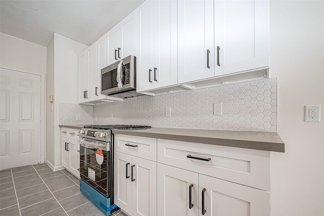 kitchen featuring tile patterned flooring, appliances with stainless steel finishes, tasteful backsplash, and white cabinetry