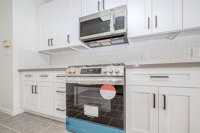 kitchen featuring tasteful backsplash, white cabinets, stainless steel appliances, and light tile patterned floors