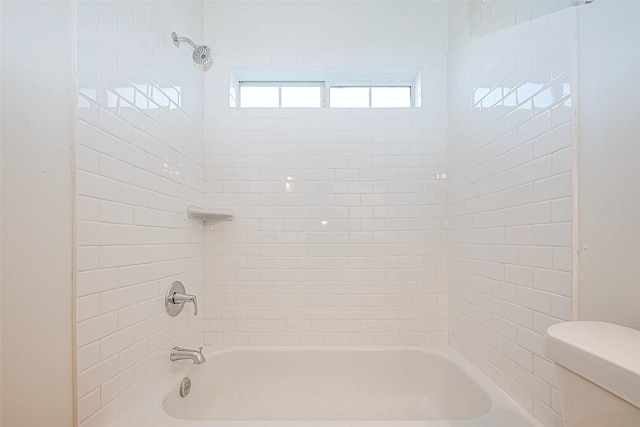 bathroom with tiled shower / bath combo and toilet