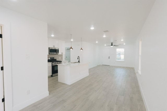 kitchen with appliances with stainless steel finishes, a kitchen island with sink, ceiling fan, decorative light fixtures, and white cabinetry