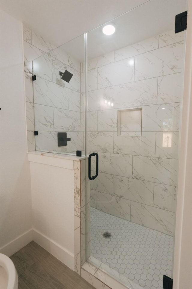 bathroom with hardwood / wood-style flooring and a shower with shower door