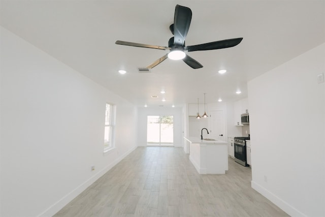 unfurnished living room with ceiling fan, sink, and light hardwood / wood-style flooring