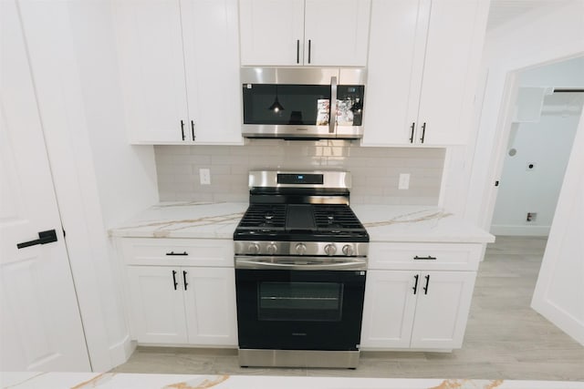 kitchen featuring white cabinetry, decorative backsplash, light stone counters, and appliances with stainless steel finishes