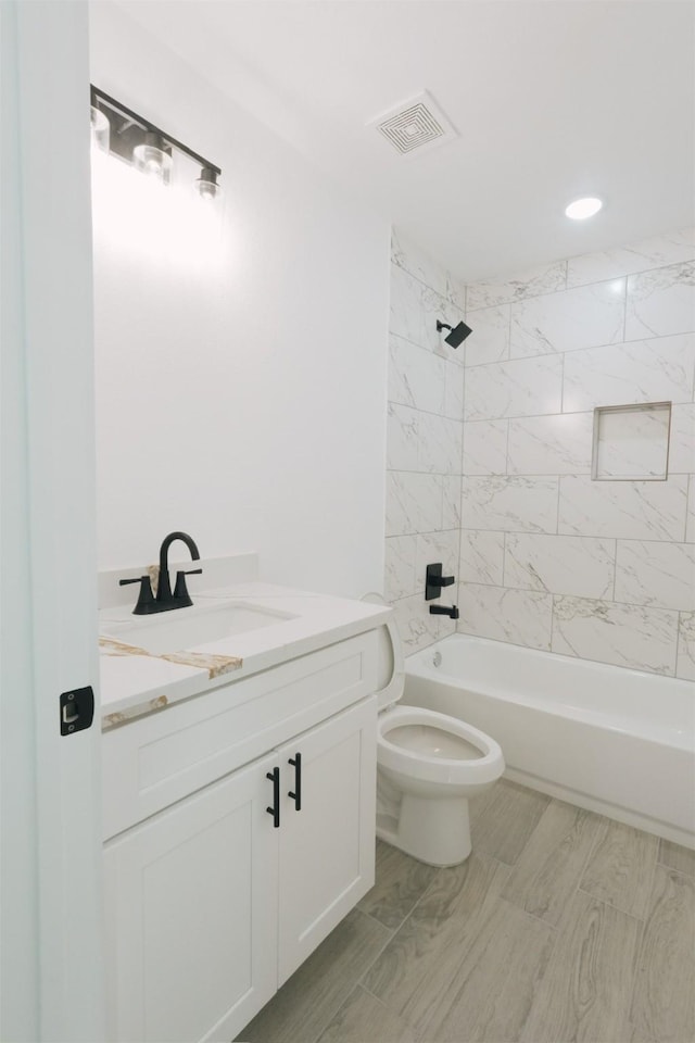 full bathroom featuring vanity, tiled shower / bath combo, and toilet