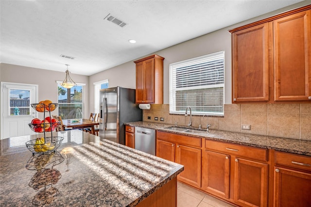 kitchen with decorative backsplash, stainless steel appliances, sink, light tile patterned floors, and dark stone countertops