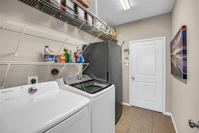 clothes washing area featuring washer and clothes dryer and light tile patterned floors