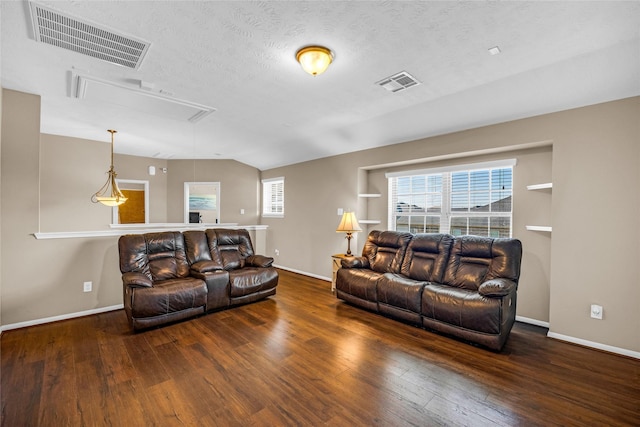 living room with a textured ceiling, built in features, and dark wood-type flooring