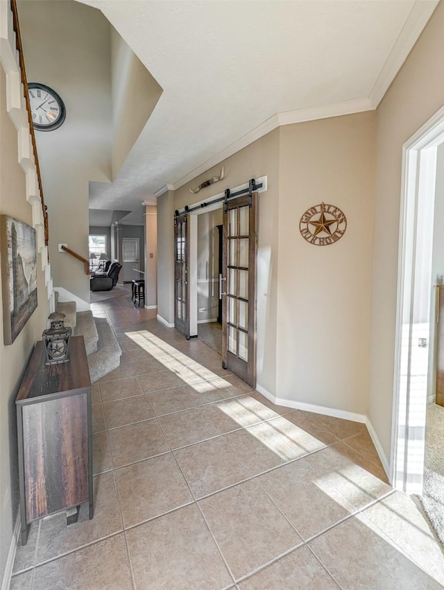 hall with a barn door, crown molding, and tile patterned flooring