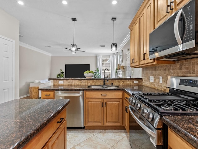 kitchen with pendant lighting, sink, dark stone countertops, ornamental molding, and appliances with stainless steel finishes