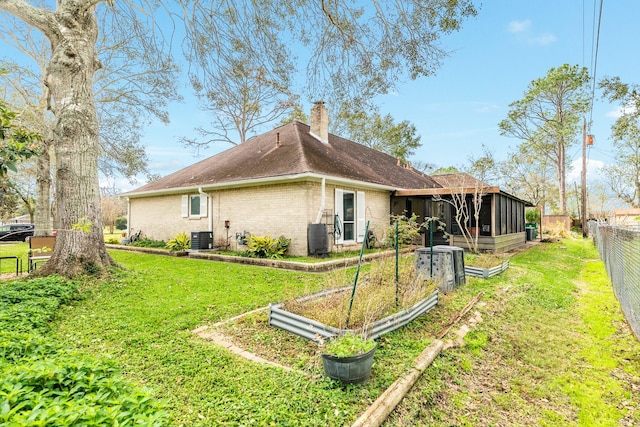 exterior space featuring a sunroom, a yard, and central AC unit