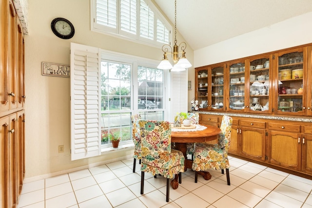 dining room with a chandelier, a healthy amount of sunlight, light tile patterned flooring, and vaulted ceiling