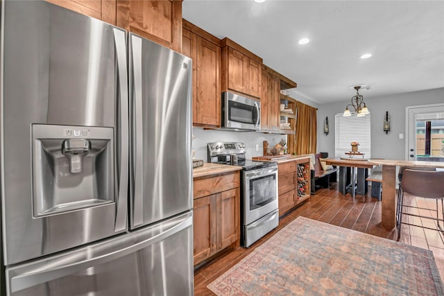 kitchen featuring wooden counters, dark hardwood / wood-style floors, a notable chandelier, decorative light fixtures, and appliances with stainless steel finishes