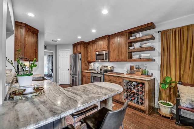 kitchen with a kitchen bar, appliances with stainless steel finishes, and kitchen peninsula